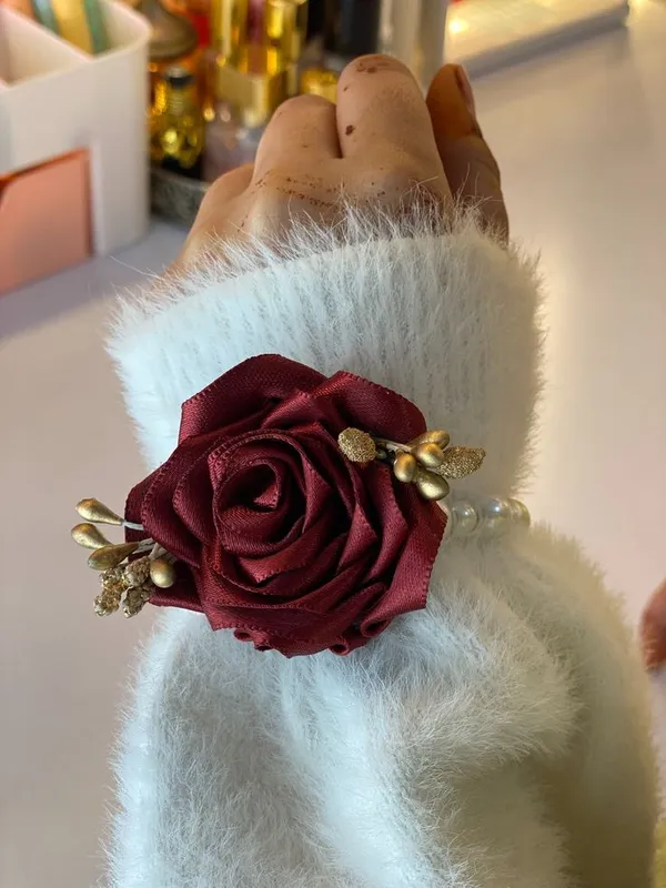 Wrist gajra with a large burgundy satin rose, gold leaves and a pearl band