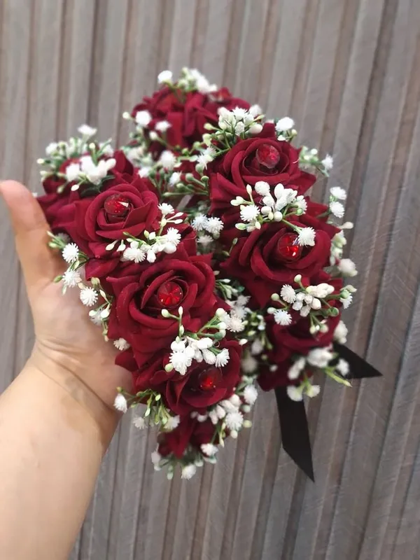 Red satin rose gajra with baby's breath held in a hand