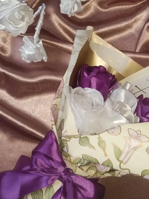 Lilac and white satin rose bouquet in a vintage floral wrap with a purple bow, made by Flora