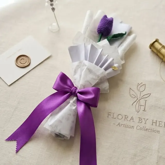 Single purple tulip stem wrapped in white with a purple satin ribbon