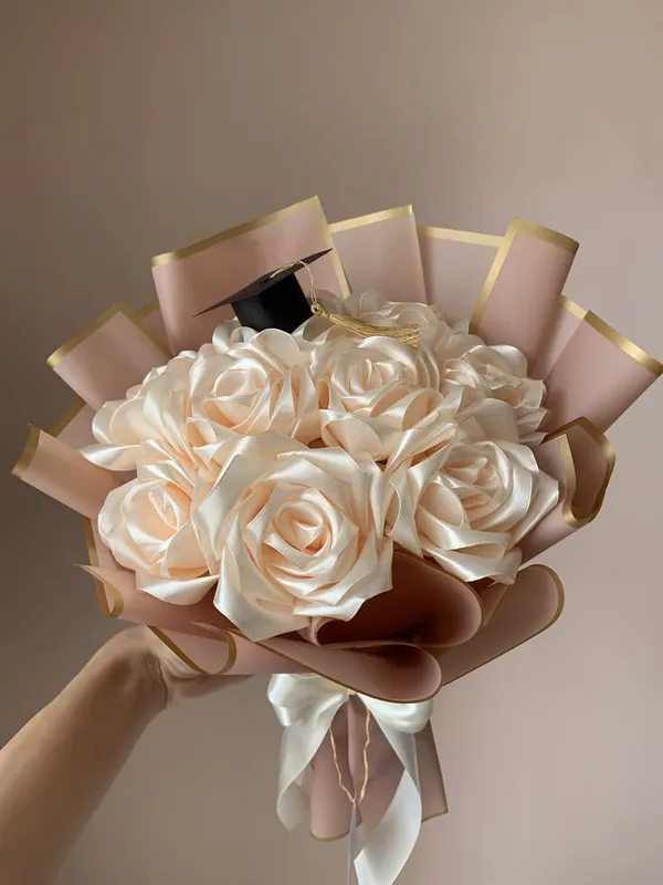 Champagne satin roses in blush wrap with a small graduation cap