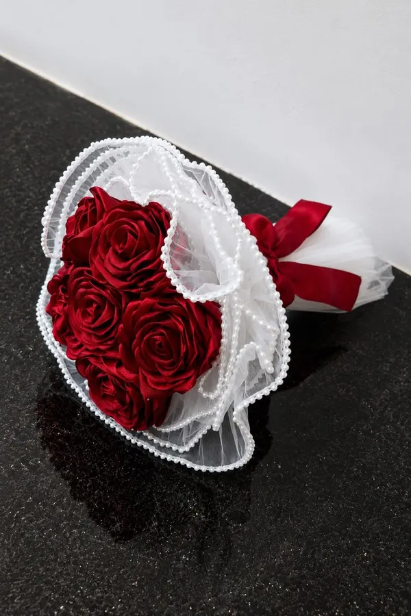 Red satin roses wrapped in white lace with a pearl trim